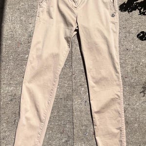 May include: Tan-colored pants with a matching belt. The pants have a button closure and pockets. The belt is a darker shade of tan. The pants are made of a lightweight material, suitable for casual wear.