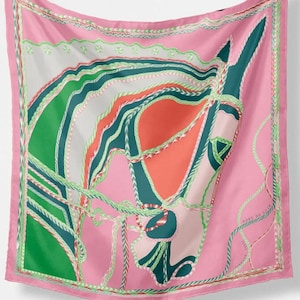 May include: A pink silk scarf with a colorful abstract design of a horse's head. The design features green, red, and white rope-like patterns. The scarf has a pink border with a white text label that reads "MADE IN ITALY".