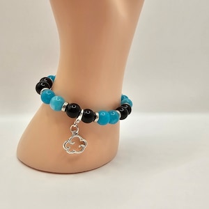 May include: A blue and black beaded bracelet with a silver cloud charm.