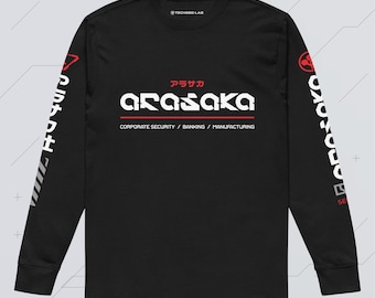 May include: A black long-sleeve shirt featuring the white text ARASAKA with red Japanese characters above it. Below the text are the words CORPORATE SECURITY / BANKING / MANUFACTURING. The sleeves have white text and red circular graphic accents.