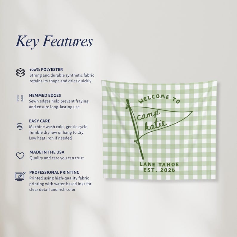 May include: A rectangular wall tapestry featuring a light green and white gingham pattern. The center displays a dark green pennant flag graphic with the text Welcome to camp katie and Lake Tahoe Est. 2026 printed in a dark green sans-serif font.