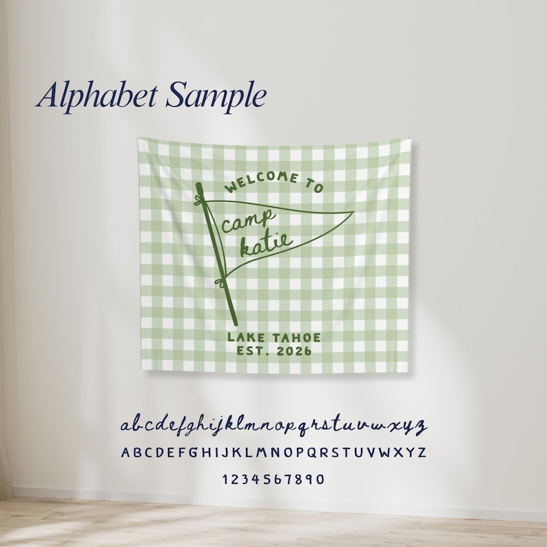 May include: A light green and white gingham wall tapestry featuring a dark green pennant graphic with the text Welcome to camp katie, Lake Tahoe, Est. 2026. Below the tapestry, the alphabet in lowercase and uppercase letters and numbers 0-9.