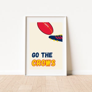 Op de afbeelding: Ingelijste print met een rood en gele voetbal en een blauw en gele schoen. De woorden "GO THE CROWS" zijn gedrukt in blauw en geel. Het kunstwerk wordt op een witte muur getoond.