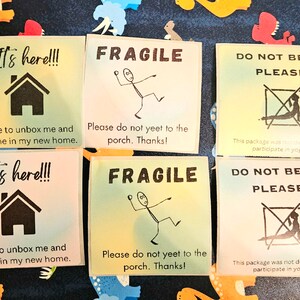 May include: Six colorful stickers with different messages. The stickers are printed with black text and graphics. The text on the stickers reads "It's here!!! Time to unbox me and put me in my new home." and "FRAGILE Please do not yeet to the porch. Thanks!" and "DO NOT BEND PLEASE This package was not designed to participate in yoga."
