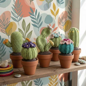 Può includere: Una collezione di cactus all'uncinetto fatti a mano in varie forme e dimensioni, ciascuno in un vaso di terracotta. I cactus sono verdi con accenti floreali colorati. L'esposizione è su una mensola di legno contro una carta da parati a motivi.