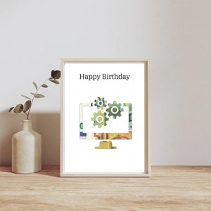 May include: A framed print with the words "Happy Birthday" at the top. The image features a computer monitor design with gears, filled with colorful currency. A vase with a plant sits to the left.