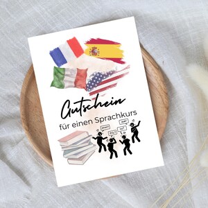 Op de afbeelding: Een witte kaart met een aquarel-illustratie van vlaggen uit verschillende landen, waaronder de Verenigde Staten, Frankrijk, Spanje en Italië. De kaart zegt "Gutschein für einen Sprachkurs" wat vertaalt naar "Voucher voor een taalcursus". Er zijn stokpoppetjes met spraakballonnen die "What?", "Oui?", "¿Hola?" en "Ne?" zeggen.