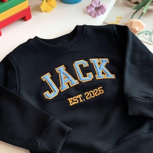 May include: Black sweatshirt with a blue and yellow embroidered "JACK" and "EST. 2025" text.