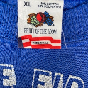 May include: A blue Fruit of the Loom sweatshirt with a white "FIR" logo. The tag says "XL", "50% Cotton", "50% Polyester", and "Made in U.S.A."