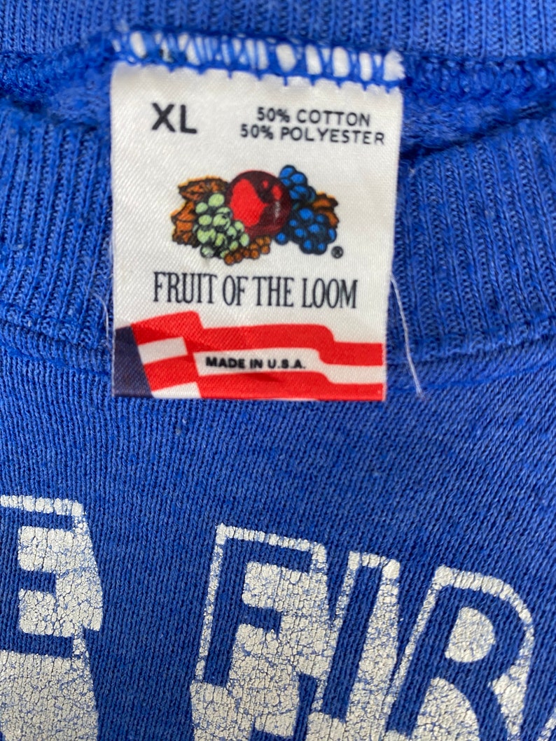 May include: A blue Fruit of the Loom sweatshirt with a white "FIR" logo. The tag says "XL", "50% Cotton", "50% Polyester", and "Made in U.S.A."