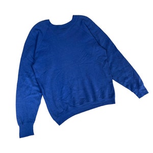 May include: A royal blue long-sleeved sweatshirt with a crew neck and raglan sleeves.