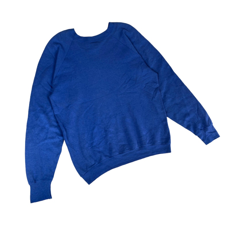 May include: A royal blue long-sleeved sweatshirt with a crew neck and raglan sleeves.