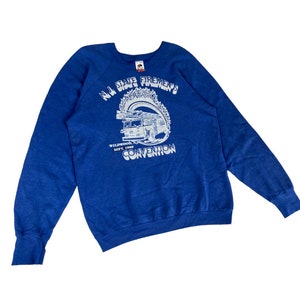 May include: A blue sweatshirt with a white graphic of a fire truck and the text "N.J. State Firemen's Convention" with the date "Sept. 1989" and location "Wildwood, N.J."