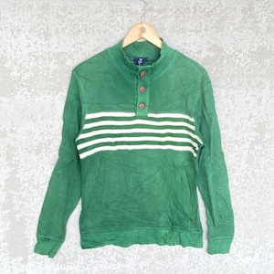 Könnte beinhalten: Grünes Langarmshirt mit Stehkragen und drei braunen Knöpfen. Das Shirt hat drei horizontale weiße Streifen über der Brust. Das Shirt hängt an einem Holzbügel.