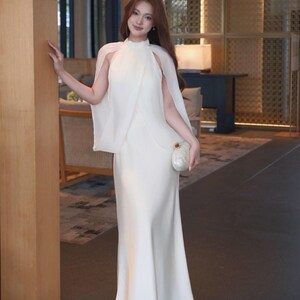 white dress with cape overlay Elliatt Poppy Layered Gown Maxi Celebrate your love story in this beautifully designed piece that embodies modern elegance. Metallic Cape Overlay Flowing Performance
