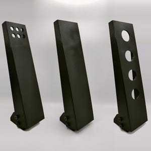May include: Three black metal pedal plates with different hole patterns. The plates are angled and have a textured surface.