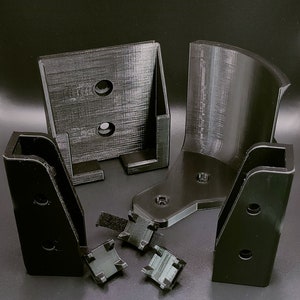 May include: A set of black plastic parts for a 3D printed project. The parts include a curved piece, a flat piece with two holes, and two rectangular pieces with holes. There are also four small black plastic pieces with velcro.