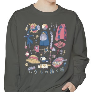 May include: A dark green sweatshirt with a graphic print of various items from the anime film "Howl's Moving Castle". The text "ハウル の 動く 城" is printed on the bottom of the graphic.