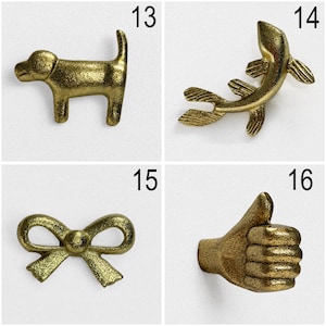 May include: A set of four brass-toned metal wall hooks featuring distinct shapes: a dog silhouette labelled 13, a fish shape labelled 14, a decorative bow labelled 15, and a hand making a thumbs-up gesture labelled 16, all with a textured finish.