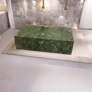 Peut inclure: Une grande dalle de marbre vert repose sur une plateforme en bois clair. La plateforme est entourée d'un sol carrelé gris clair.