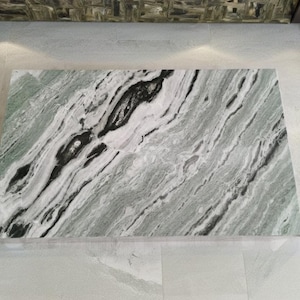 May include: A large, rectangular slab of green and white marble with black veins. The marble has a polished finish and is suitable for use as a worktop or table top.