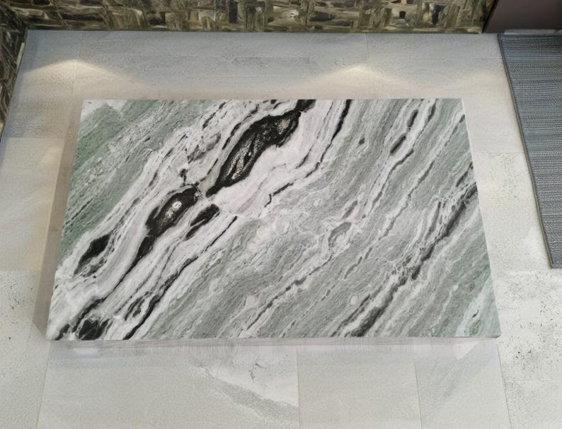 May include: A large, rectangular slab of green and white marble with black veins. The marble has a polished finish and is suitable for use as a worktop or table top.