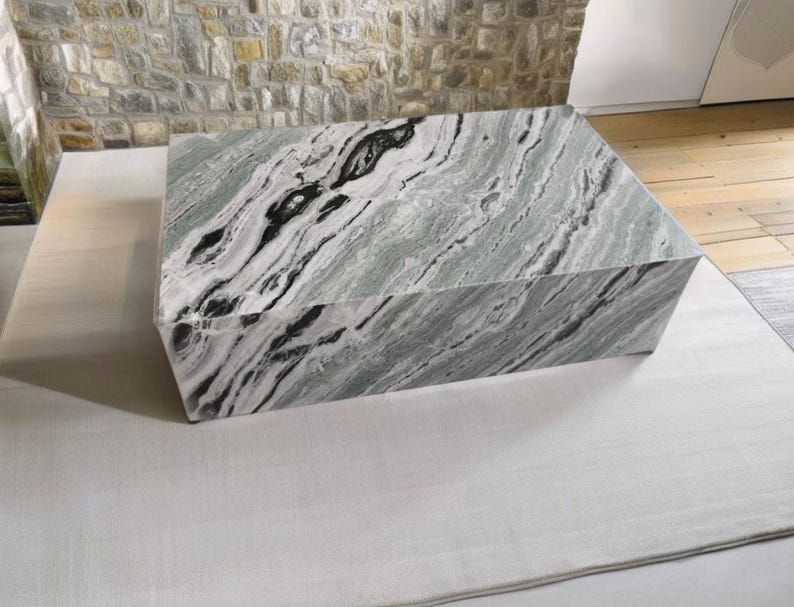May include: A large, rectangular, green and black marble pedestal. The marble has a swirling pattern of black and white veins.