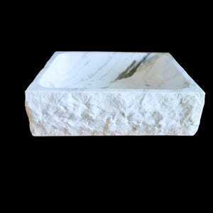 lavabo da appoggio in marmo di carrara, il lavabo è grezzo esternamente e lucido internamente, scavato da un blocco di marmo naturale, con venature grigio scuro internamente