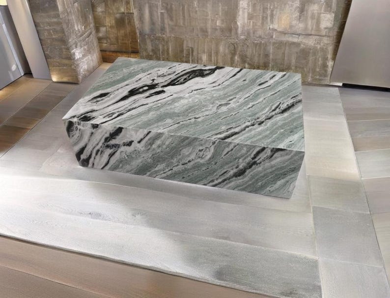 May include: A large, rectangular, green and black marble coffee table with a swirling pattern. The table is sitting on a light grey tiled floor.