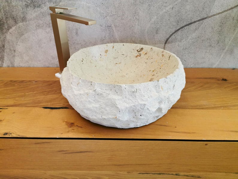 Vista frontale del lavabo da bagno in pietra naturale beige con esterno grezzo e bordo irregolare