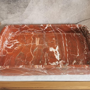 May include: A rectangular, red and white marble sink with a smooth, polished surface.