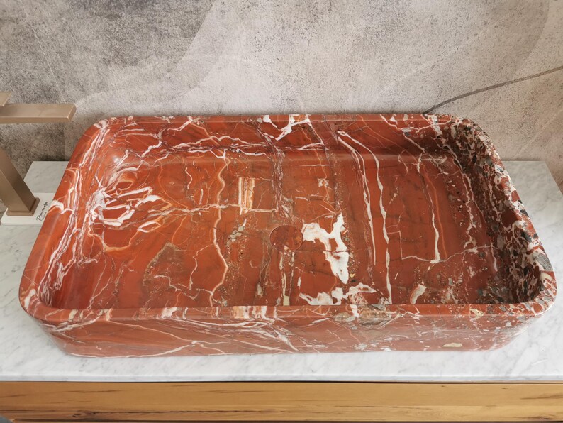 May include: A rectangular, red and white marble sink with a smooth, polished surface.