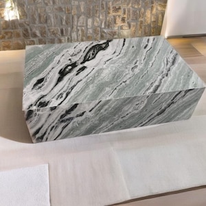 May include: A large, rectangular coffee table made of green and white marble with black veins. The table has a smooth, polished surface.