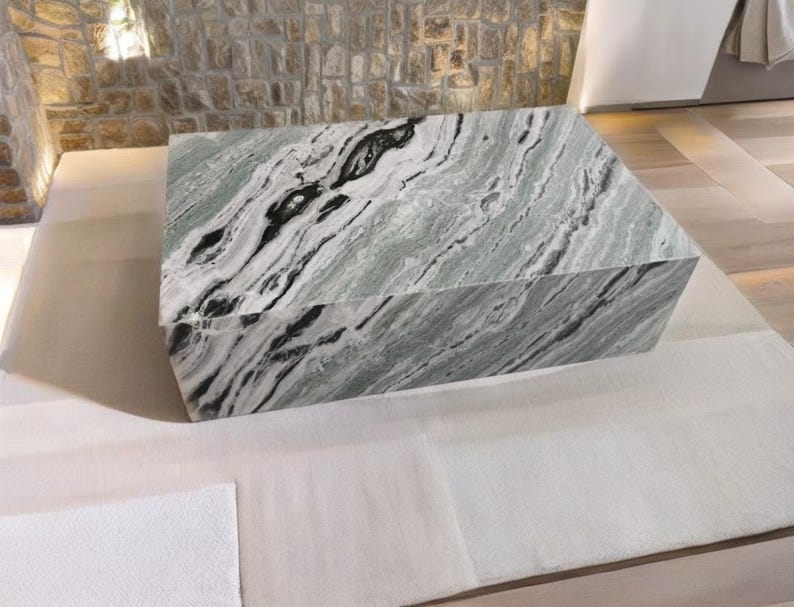 May include: A large, rectangular coffee table made of green and white marble with black veins. The table has a smooth, polished surface.