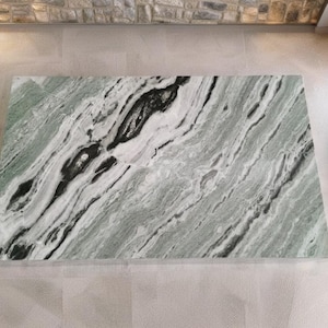 May include: A large slab of green and white marble with black veins. The marble has a polished finish and is suitable for use in a variety of applications, such as countertops, floors, and walls.