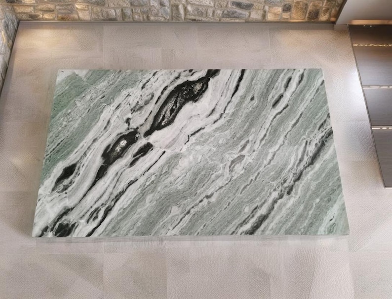 May include: A large slab of green and white marble with black veins. The marble has a polished finish and is suitable for use in a variety of applications, such as countertops, floors, and walls.