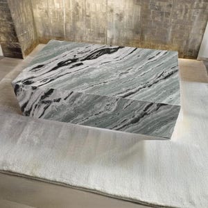 May include: A large, rectangular coffee table with a green and black marble top. The table is sitting on a light grey rug.