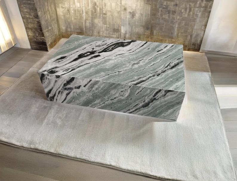 May include: A large, rectangular coffee table with a green and black marble top. The table is sitting on a light grey rug.