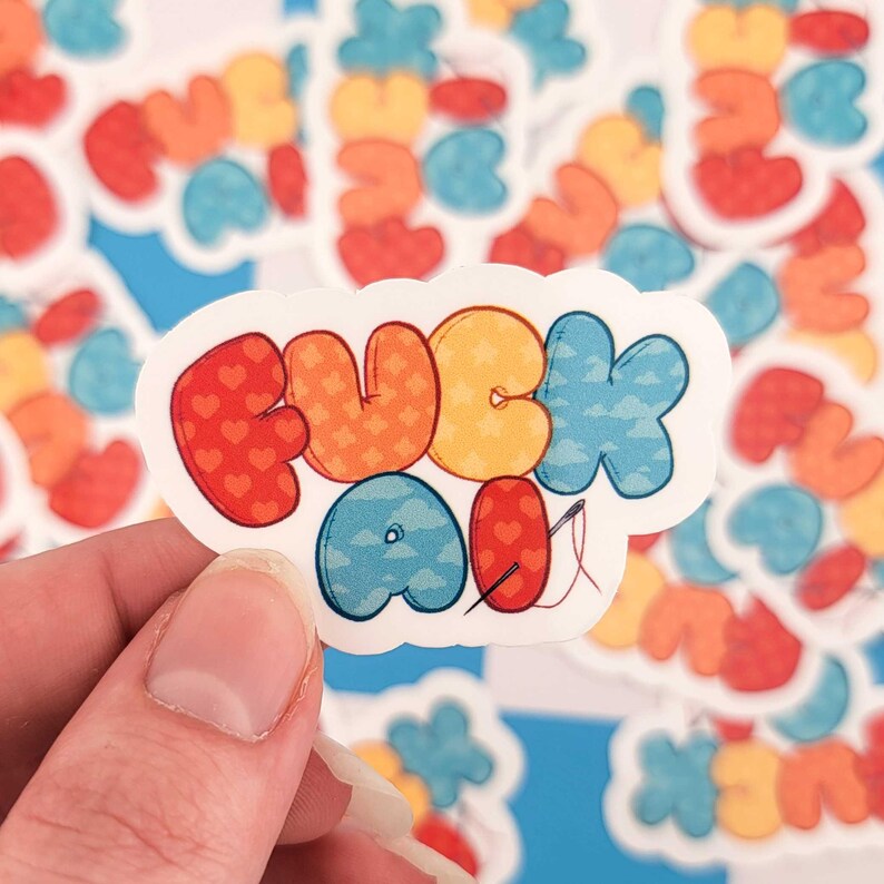 Puede incluir: Una pegatina colorida con la frase "FUCK ALL" en letras de burbujas. Las letras est&aacute;n decoradas con patrones variados, incluyendo corazones, estrellas y nubes. Tambi&eacute;n se incluye una aguja e hilo.