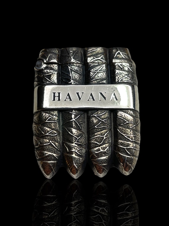 An exceptional silver vesta (match striker) in the shape of four Havana cigars. Engraved 'Havana' on both sides. Hinged lid.