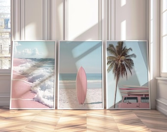 May include: A set of three framed wall art prints featuring coastal scenes. The left print shows waves on a pink sand beach. The center print displays a pink surfboard standing upright on a sandy beach. The right print depicts a palm tree and a pink van.