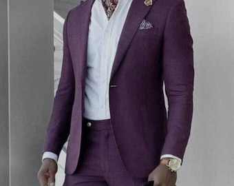 May include: A formal purple suit with a white dress shirt and patterned neckwear. The suit includes a blazer and matching trousers. The outfit is completed with white shoes and a gold watch. A pocket square adds a touch of elegance.