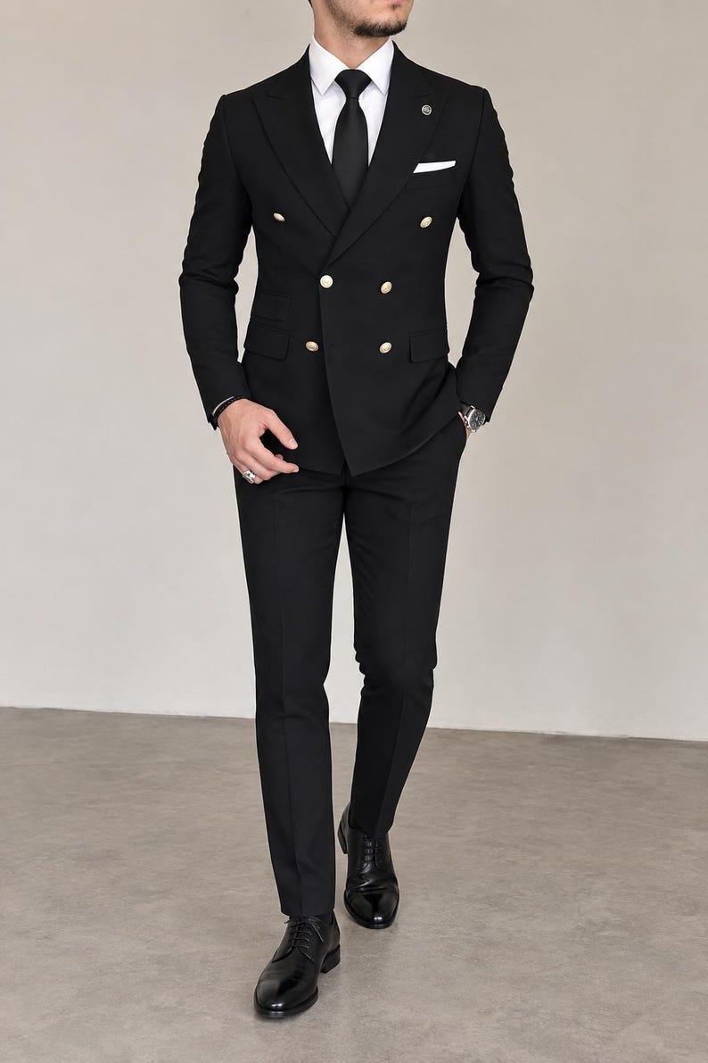 May include: A black double-breasted suit featuring gold-toned buttons, a white dress shirt, and a black necktie. The ensemble includes matching black trousers and polished black leather dress shoes, creating a formal and structured appearance.