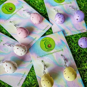 Könnte beinhalten: Handgefertigte Ohrringe aus Sterlingsilber in Form von gesprenkelten Eiern in verschiedenen Farben wie Rosa, Lila, Gelb und Weiß. Jeder Ohrring ist an einer Karte mit dem Text "ForeverGreenJewellery.co.uk" und "Handmade" befestigt.
