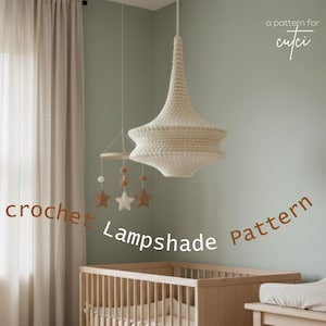Op de afbeelding: Een kinderkamer met een houten wieg, een gehaakte lampenkap en een mobiel met ster- en kraalaccenten. De kamer heeft een neutraal kleurenpalet met de tekst "crochet Lampshade Pattern".