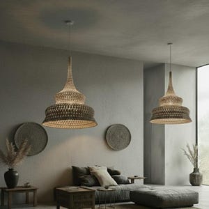May include: Two woven pendant lights with a tiered design hang from the ceiling. The lampshades are a light brown color and have a textured appearance. The room is decorated in neutral tones with a sofa, decorative wall hangings, and vases.