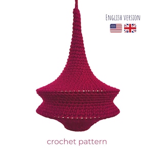 May include: A crochet pattern for a red, crocheted lampshade. The lampshade is shaped like a spinning top and has a pointed top. The pattern is available in both English and American English.