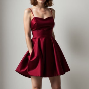 May include: A short, sleeveless, burgundy satin dress with a scoop neckline and a flared skirt.
