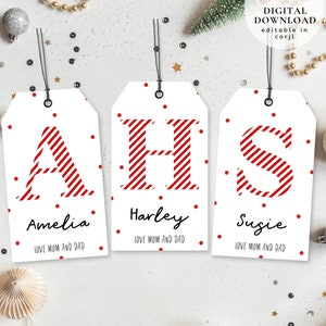 Puede incluir: Tres etiquetas de regalo blancas con letras rayadas rojas y blancas que deletrean "AHS". Cada etiqueta tiene lunares rojos y los nombres "Amelia", "Harley" y "Susie" con el texto "Love Mom and Dad".
