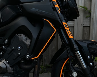 May include: A black motorcycle with orange accents. The motorcycle has a Yamaha logo on the side and MT-09 written on the front forks.